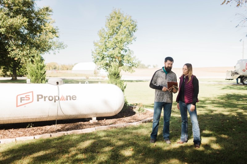 propane specialist assisting homeowner in front of fs propane tank